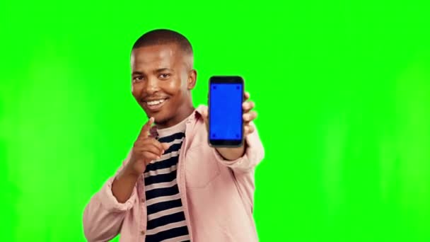 Boldog fekete férfi, mutató és telefon mockup a zöld képernyőn a reklám a stúdió háttér. Portré afrikai férfi személy bemutató mobil okostelefon app nyomkövető markerek a mock up. - Felvétel, videó
