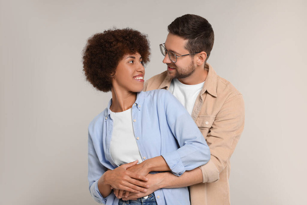 International dating. Happy couple hugging on light grey background - Photo, Image