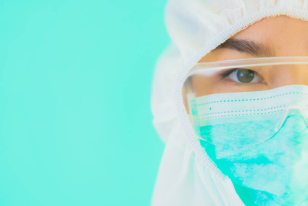 Güzel, genç Asyalı doktor kadın koronavirüsten korunmak için ppe ya da kişisel koruyucu ekipman takıyor ya da mavi izole arka planda beyaz kartı olan 19. bölgede yaşıyor. - Fotoğraf, Görsel