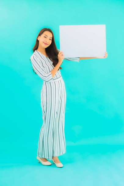 Retrato hermosa joven asiática mujer show blanco vacío valla publicitaria en azul aislado fondo - Foto, imagen