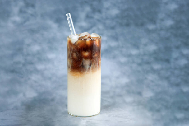 グラスストローとトールグラスにアイスコーヒー. ロシアのテーブルの上の氷のキューブと豆. コピースペースと冷たい夏の飲み物. - 写真・画像