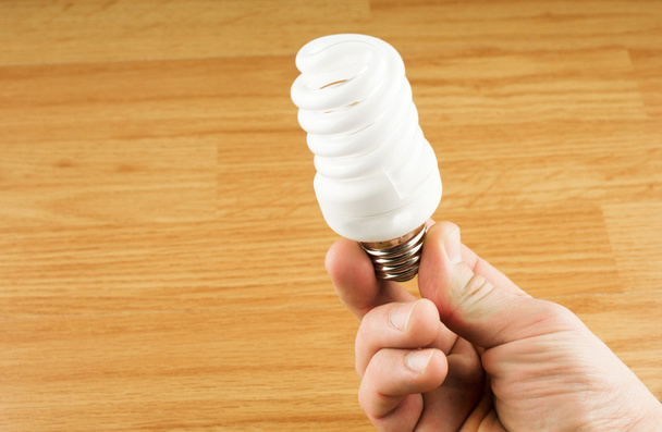 Luminescent light bulb in his hand  - Fotó, kép