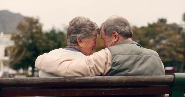 Láska, náklonnost a starší pár na lavičce objímající se pro spojení, závazek nebo péči v zahradě. Příroda, šťastný a starší muž a žena v důchodu objímající na intimní okamžik v parku. - Záběry, video