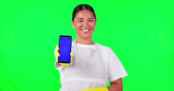 Mujer asiática, ama de llaves y maqueta de teléfono en la pantalla verde en la publicidad contra un fondo de estudio. Retrato de persona femenina feliz, criada o limpiador mostrar aplicación de teléfono inteligente móvil con marcadores de seguimiento. - Metraje, vídeo