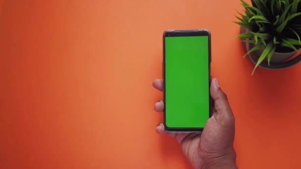 vista superior de la mano del hombre joven utilizando el teléfono inteligente con pantalla verde . - Imágenes, Vídeo