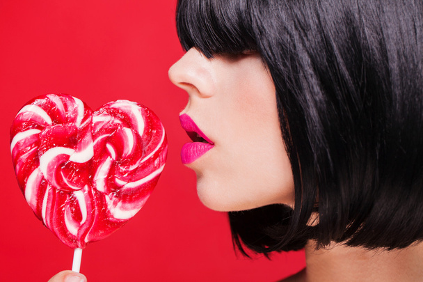 Closeup photo of a beautiful sexy pink lips with lollipop - Foto, afbeelding