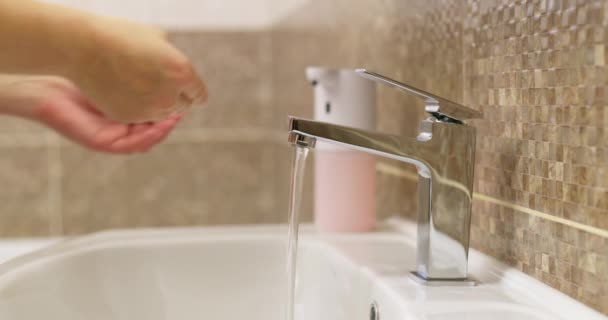 Vrouw wast haar handen grondig met vloeibare zeep in de badkamer thuis of in een hotel. Gezondheidsconcept, zorg voor schone handen. Hoge kwaliteit 4k beeldmateriaal - Video