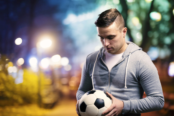 Спортсмен тримає футбольний м'яч
 - Фото, зображення