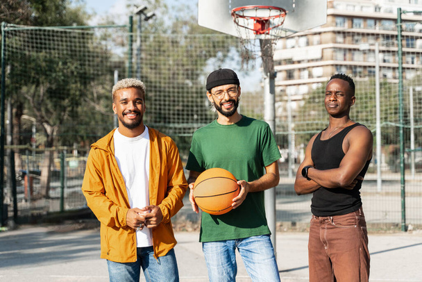 Portrait of smiling young African American friends on outdoors urban basketball sport court - Photo, Image