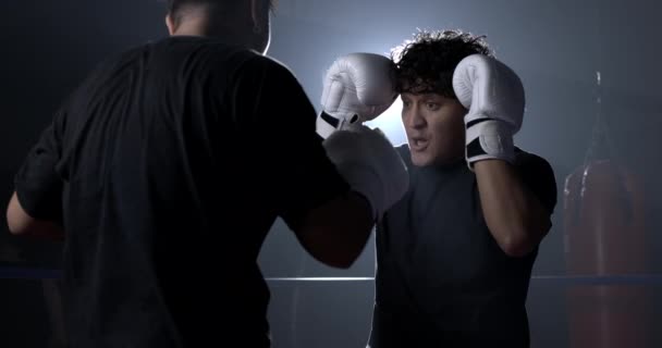 Boksers in de ring dragen handschoenen, vechten rivalen in intense face to face - Video