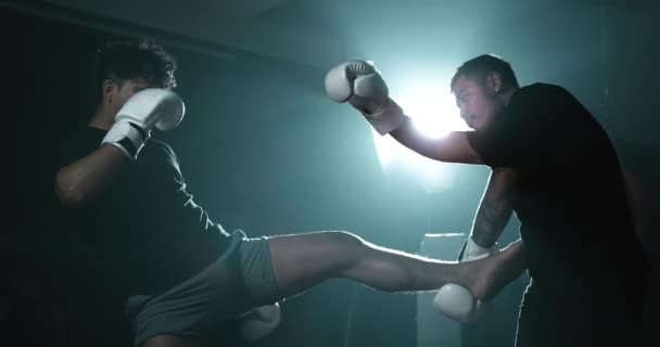 Due uomini all'interno dell'anello impegnati in una lotta utilizzando la tecnica di combattimento Muay Thai. Gli avversari indossano guanti da pugilato che colpiscono calci e pugni in super slow-motion a 800 fps - Filmati, video