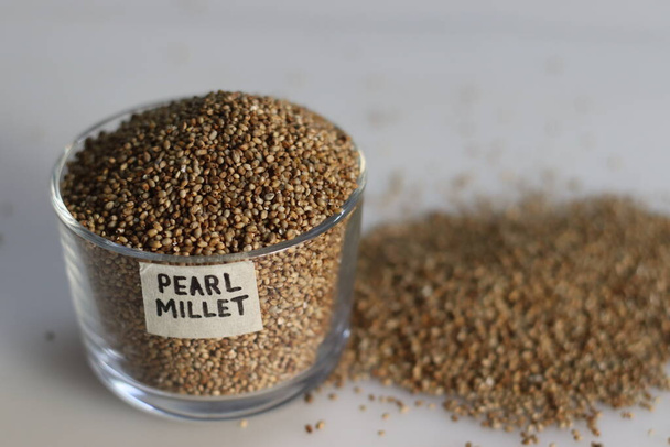 Pearl millet grains in a glass bowl with label on it filled to the brim, showcasing their pearl like natural beauty and healthy nutrition. Ideal for food and agriculture concepts - Photo, Image
