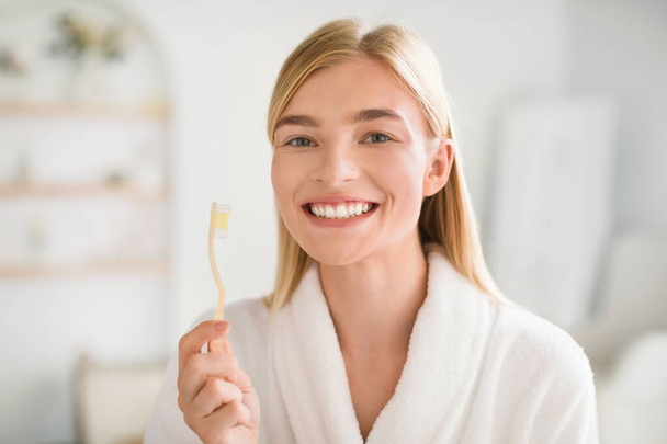 Perfect Smile. Happy Young Blonde Woman Posing With Toothbrush Brushing Teeth Looking At Camera In Modern Bathroom Indoors. Oral Hygiene Routine, Toothpaste And Toothcare Products Advertisement - Foto, afbeelding