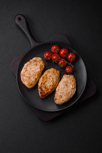 Delicious fresh chicken cutlets or meatballs with salt, spices and herbs on a dark concrete background - Photo, Image