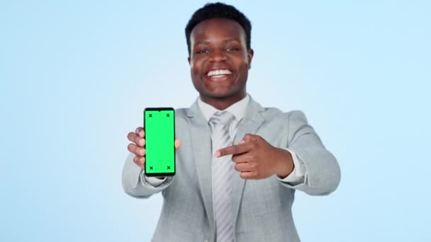 Телефон, зелений екран і бізнесмен з рукою вказують в студії для новин, інформації або реклами на синьому фоні. Смартфон, відображення та портрет африканського підприємця-чоловіка, який показує реєстрацію, додаток або пропозицію. - Кадри, відео