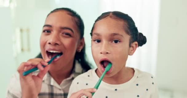 Brushing teeth, mother and daughter with toothbrush and dental for health, morning routine and happy face. Healthy, hygiene and portrait, woman and young girl, oral care and cleaning mouth at home. - Footage, Video
