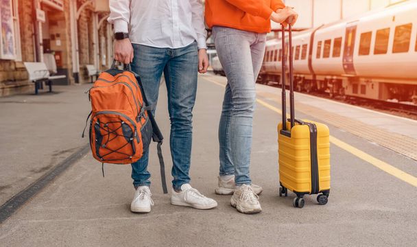 Reizigers met een rugzak en gele koffer wachten op een trein op het station. Het echtpaar miste de trein. Reisconcept. - Foto, afbeelding