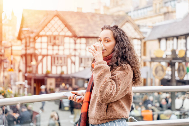 fiatal nő dzsekiben és narancssárga sál iszik egy kávét, Életmód fotó és barátkozás barátaival egy európai városban - Fotó, kép