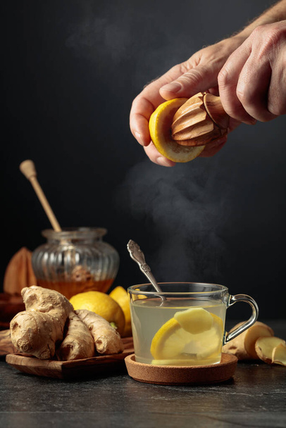 Té jengibre con limón y miel. El jugo se exprime de un limón con un exprimidor de madera viejo. - Foto, imagen