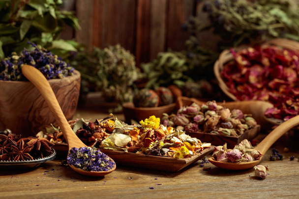 Diverse gedroogde geneeskrachtige planten, kruiden en bloemen op een oude houten achtergrond. Concept van kruidengeneeskunde of aromatherapie. - Foto, afbeelding