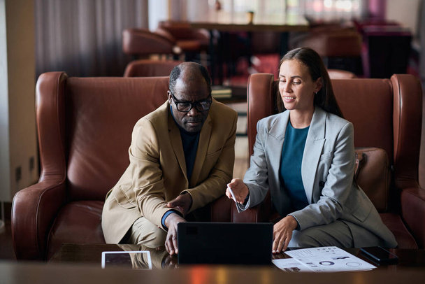 Επαγγελματικό ζευγάρι που εργάζεται online σε laptop κατά τη διάρκεια της συνάντησής τους στο ξενοδοχείο - Φωτογραφία, εικόνα