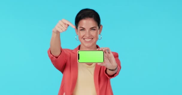 Yeşil ekran telefon, yüz ve mutlu kadın tanıtım, marka sunumu ve mobil uygulamayı gösteriyor. Portre, akıllı telefon bağlantısı ve kişi jesti mavi arkaplanda çevrimiçi serviste. - Video, Çekim