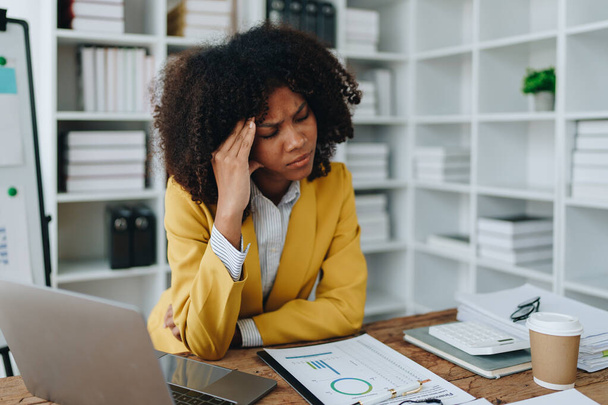 Burnout Amerykański afrykański biznes kobieta w stresie pracuje z wielu dokumentów papierkowej roboty, atak migreny, Freelance, praca w biurze. - Zdjęcie, obraz
