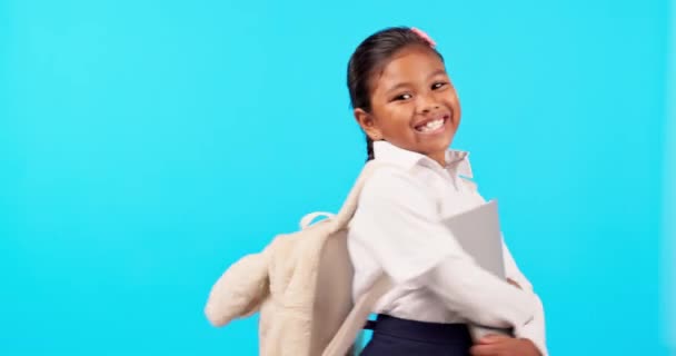 School, boeken en portret van meisje enthousiast voor onderwijs of huiswerk geïsoleerd in een studio blauwe achtergrond. Leren, ontwikkelen en kind of jong kind gelukkig in uniform houden leerboek met een glimlach. - Video