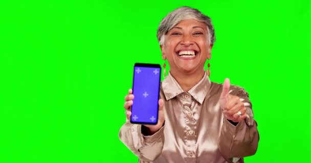Великі пальці вгору, телефон і жінка в студії з зеленим екраном на технології для маркетингу або реклами. Щаслива, посмішка і портрет старшої жіночої моделі з мобільним телефоном з маркерами стеження і макетування
 - Кадри, відео