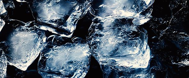 Water splashing and ice cube. Ice splashing into a glass of water. Underwater pouring ice cubes falling into clear watering background. Refreshing chill drinking. Ices in a glass with blue background - Photo, Image