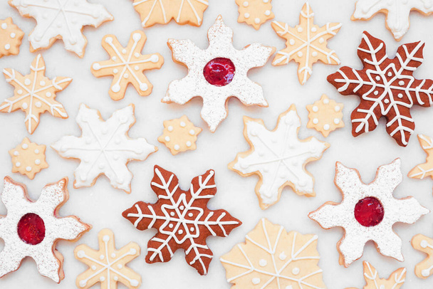 Karácsonyi sütés háttér a különböző hópihe cookie-k. Felül nézet egy fehér márvány háttér. Ünnepi sütési koncepció. - Fotó, kép