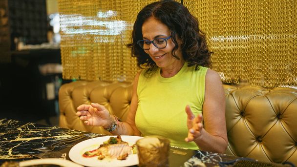 Middelbare leeftijd Spaanse vrouw die vis eet in een restaurant - Foto, afbeelding