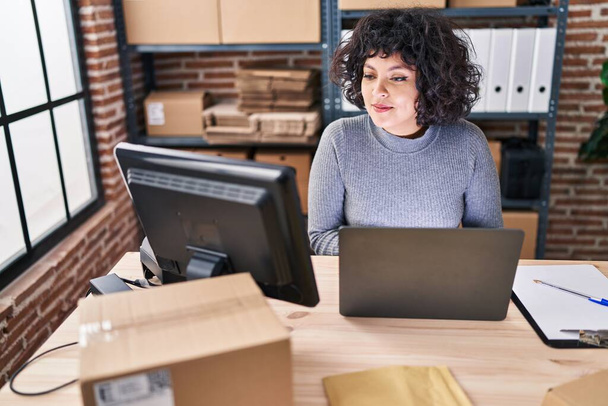 Nuori kaunis latino nainen verkkokauppa liiketoiminnan työntekijä käyttää kannettavaa tietokonetta istuu pöydällä toimistossa - Valokuva, kuva