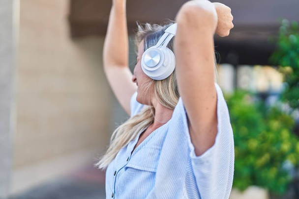 Young blonde woman listening to music and dancing at street - Fotoğraf, Görsel