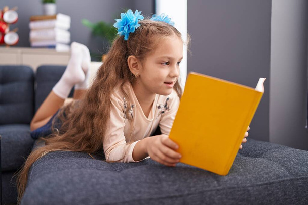 Adorabile caucasico ragazza lettura libro sdraiato sul divano a casa - Foto, immagini