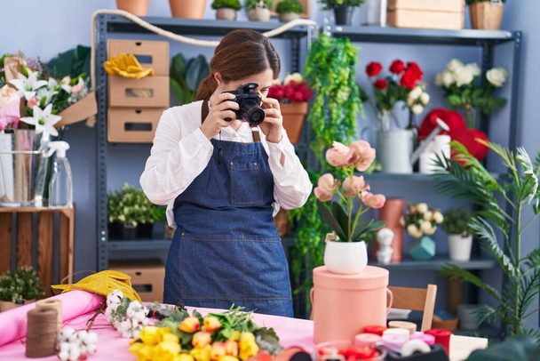 若い女性の花屋は花屋の店で花にプロのカメラで写真を撮る - 写真・画像