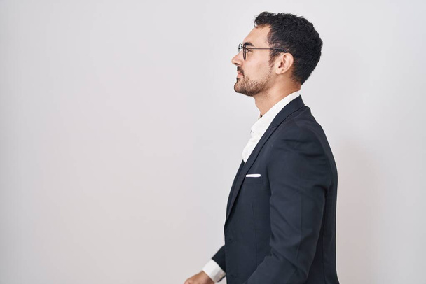 Bonito homem hispânico de negócios em pé sobre fundo branco olhando para o lado, relaxar pose perfil com rosto natural e sorriso confiante.  - Foto, Imagem