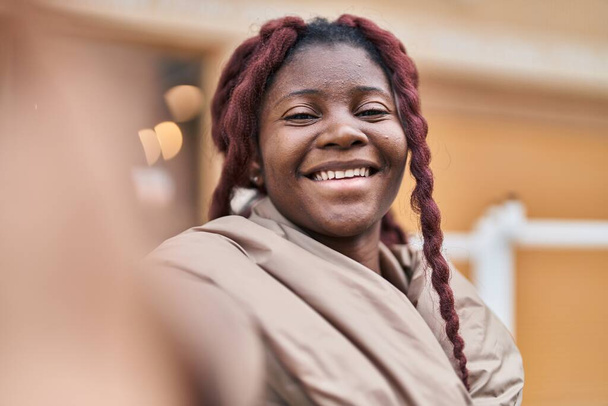 Afro-Amerikalı kadın gülümsüyor. Sokakta kamerayla özçekim yapıyor. - Fotoğraf, Görsel