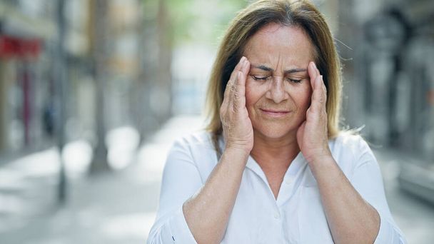 Középkorú spanyol nő szenved fejfájás az utcán - Fotó, kép