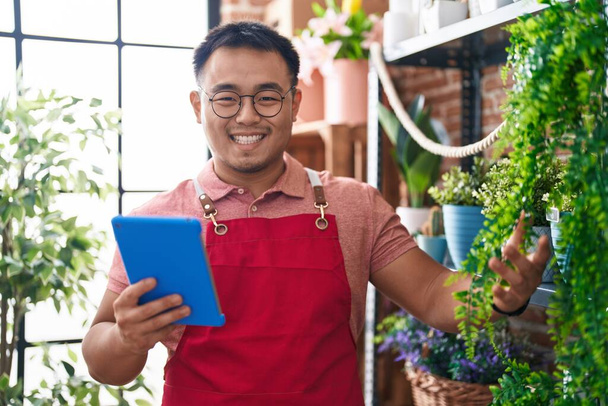 Young chinese man florist smiling confident using touchpad at florist - Photo, image