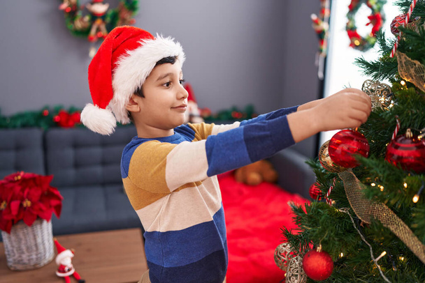 Adorable garçon hispanique souriant décoration confiante arbre de Noël à la maison - Photo, image