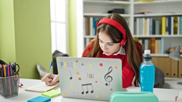 Giovane studentessa ispanica che ha lezioni online di scrittura su taccuino presso l'università della biblioteca - Foto, immagini