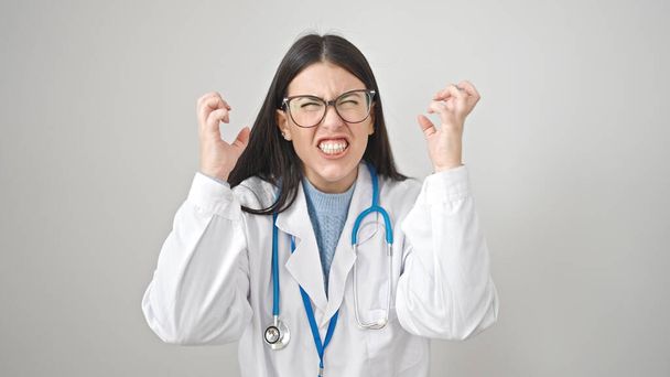 Νεαρή ισπανίδα γιατρός θυμωμένος και τόνισε πάνω από απομονωμένο λευκό φόντο - Φωτογραφία, εικόνα