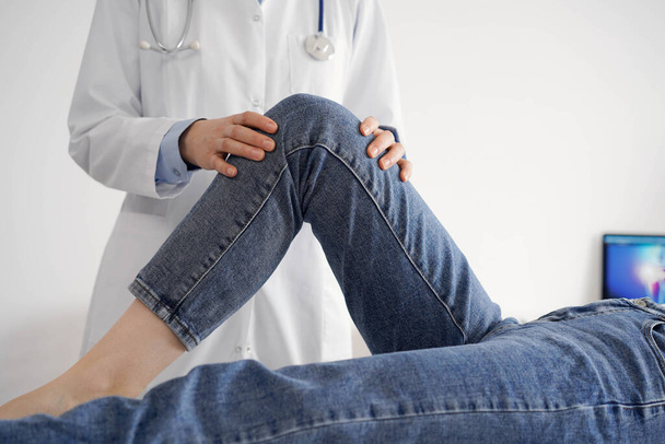 Doctor and patient are at the usual medical inspection in the clinic. Therapist examines a young womans knee. Medicine concept . - Фото, изображение