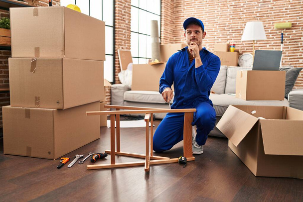 Young hispanic man working on moving service serious face thinking about question with hand on chin, thoughtful about confusing idea  - Photo, Image