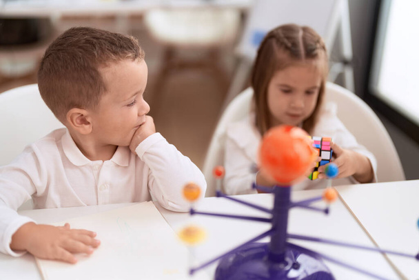 Menina adorável e menino brincando com cubo de quebra-cabeça de cor sentado na mesa no jardim de infância - Foto, Imagem