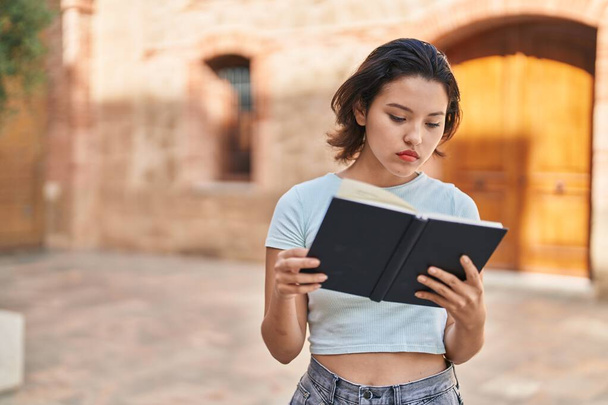 Sokakta kitap okuyan genç İspanyol kadın. - Fotoğraf, Görsel