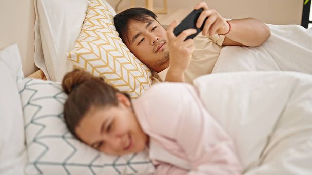 Mies ja nainen pari makaa sängyssä käyttäen älypuhelimia makuuhuoneessa - Valokuva, kuva