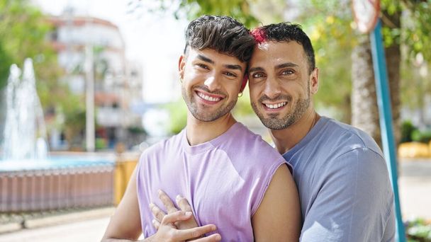 Two men couple smiling confident hugging each other at park - Photo, image
