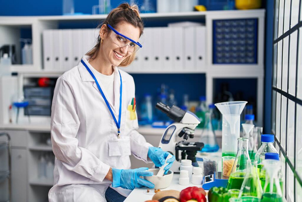 Nuori nainen tiedemies hymyilee luottavainen työskentelevät laboratoriossa - Valokuva, kuva